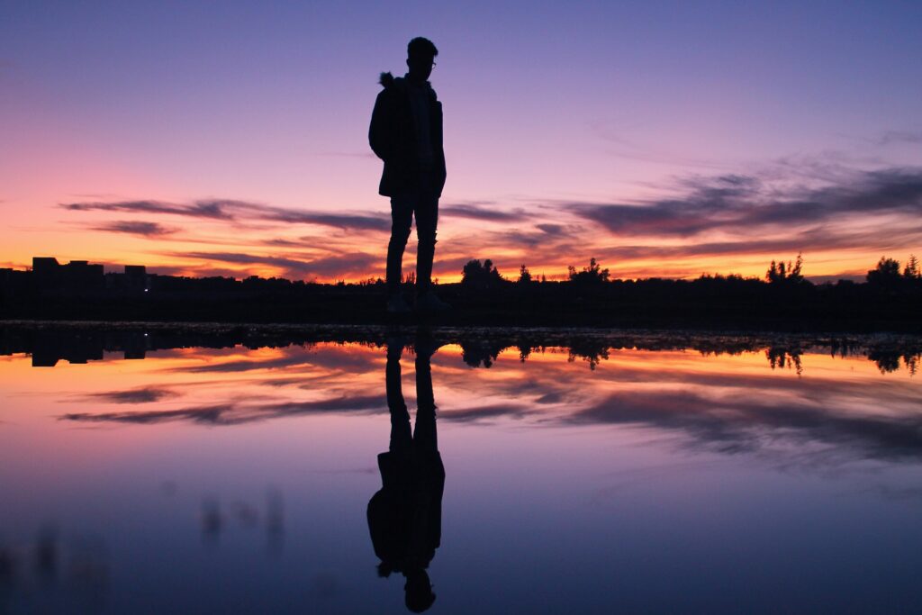 Deze afbeelding illustreert een man die zijn eigen reflectie aanschouwt als ware het een kijkje in de spiegel