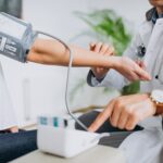 Doctor measuring a patient’s blood pressure during a health check-up (MOT).